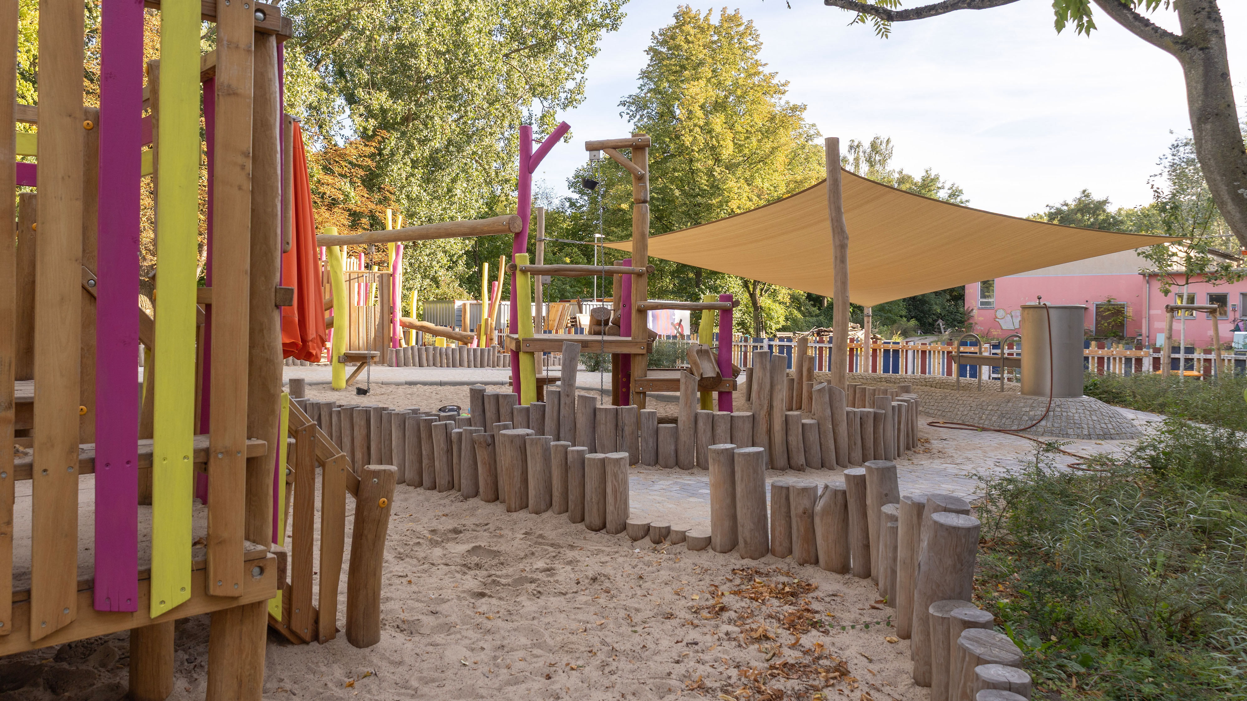 Palisaden aus Robinienstämmen fassen die verschiedenen Sandspielflächen spielerisch ein